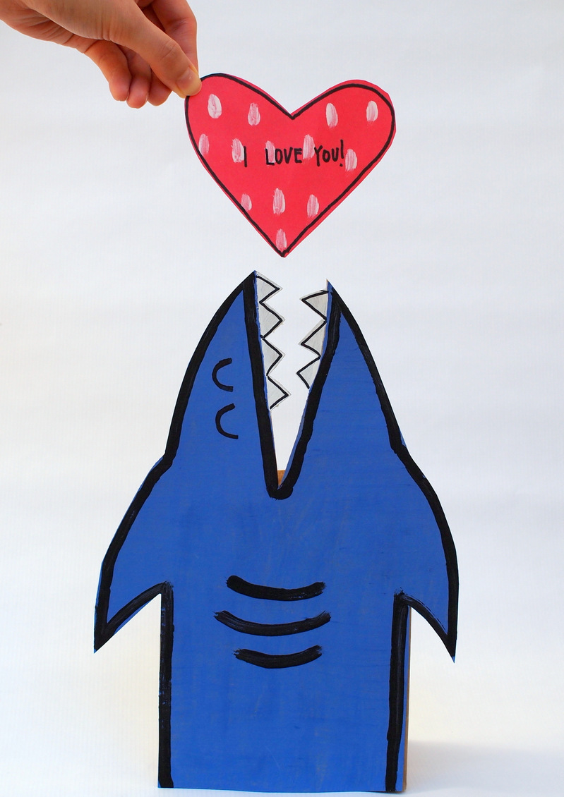 Tiburón de cartulina colocado en vertical y un corazón sobre su boca